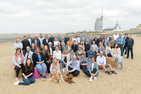 Die Mitarbeiter der BIS Bremerhaven | © BIS / Antje Schimanke Eine große Gruppe von Menschen stehen am Strand und lächeln in die Kamera | © BIS / Antje Schimanke