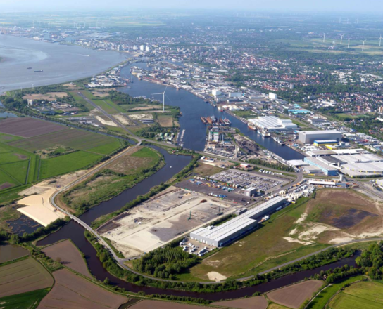 Luftansicht einer Stadt am Wasser und einer Baustelle im Vordergrund | © BIS/Scheer