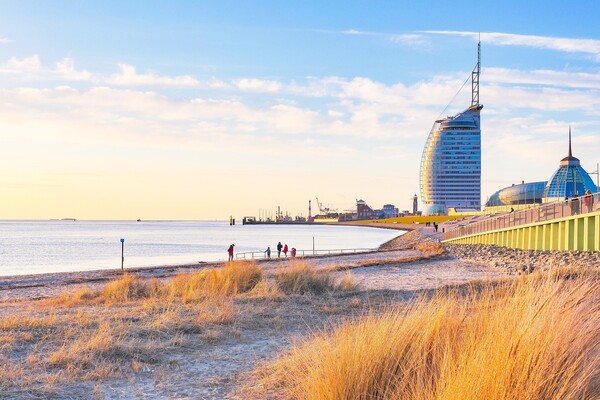 Die Skyline von Bremerhaven | © Tim Mrzyglod auf Pixabay Das Bild zeigt einen Strand und Wasser im Vordergrund sowie ein segelförmiges Gebäude am Horizont | © Tim Mrzyglod auf Pixabay